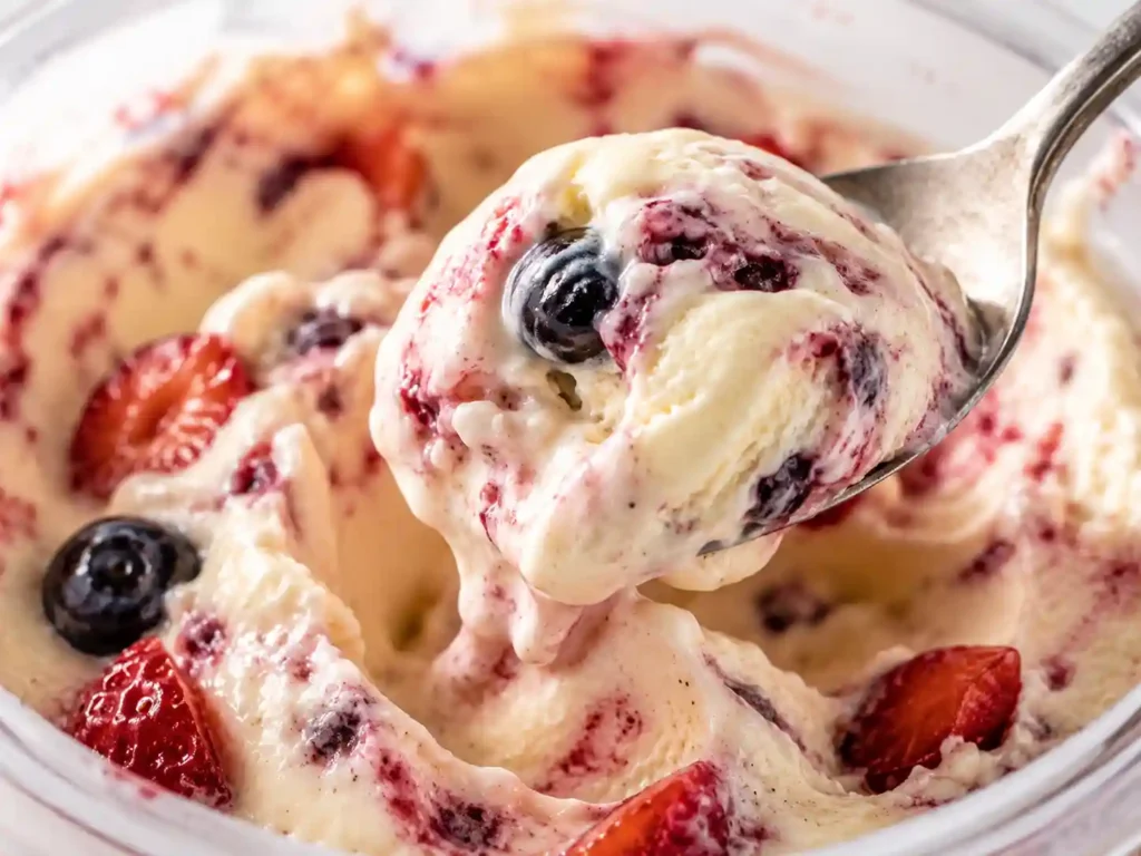 Close-up spoonful of creamy Ninja Creami protein ice cream showing a smooth thick texture with berry swirls.