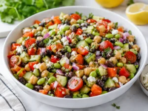 High protein dense bean salad with chickpeas, black beans, edamame, cucumber, tomatoes, herbs, and lemon dressing