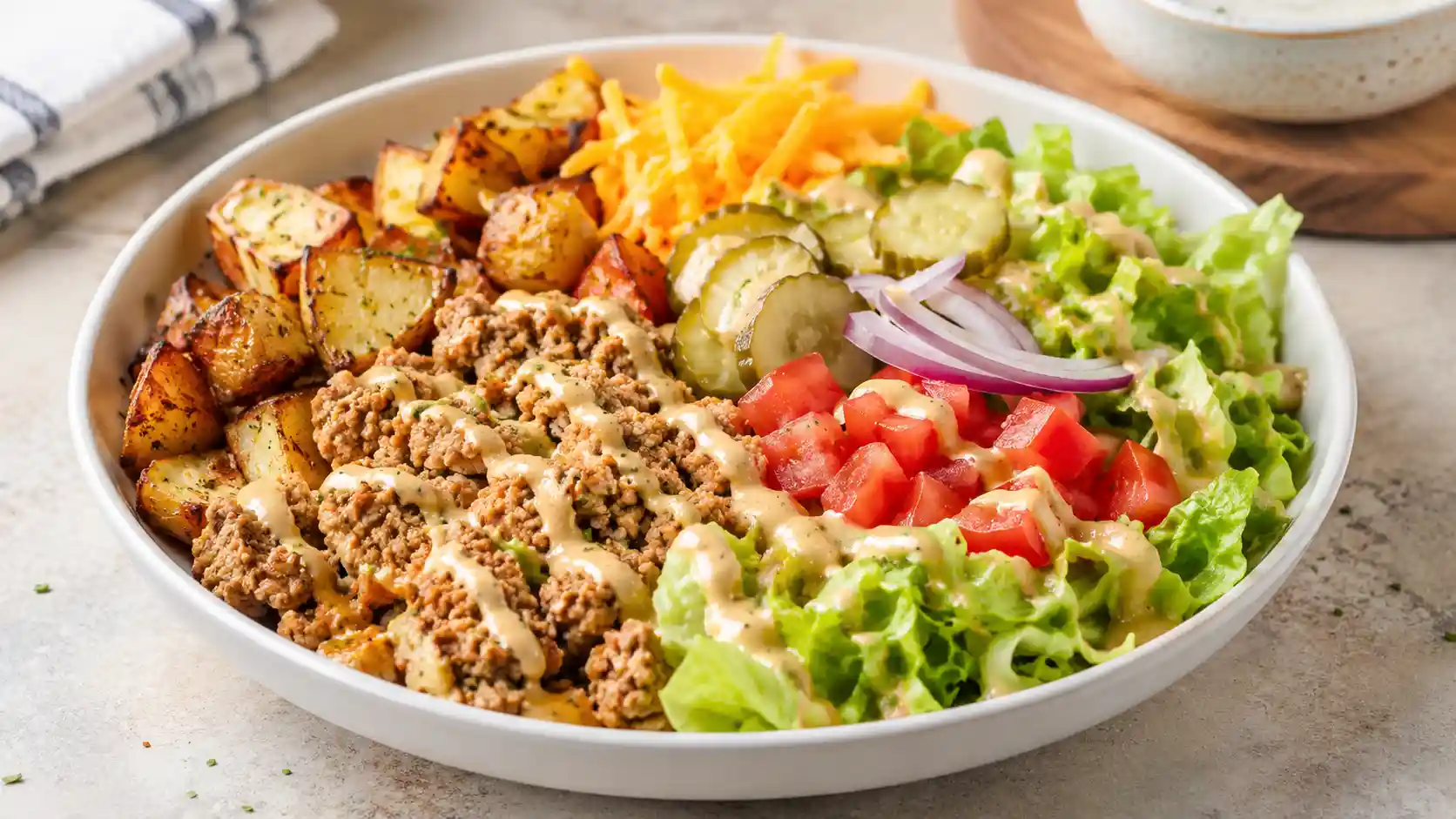 Turkey burger bowl with seasoned ground turkey, lettuce, tomatoes, pickles, red onion, cheddar, and creamy burger sauce.