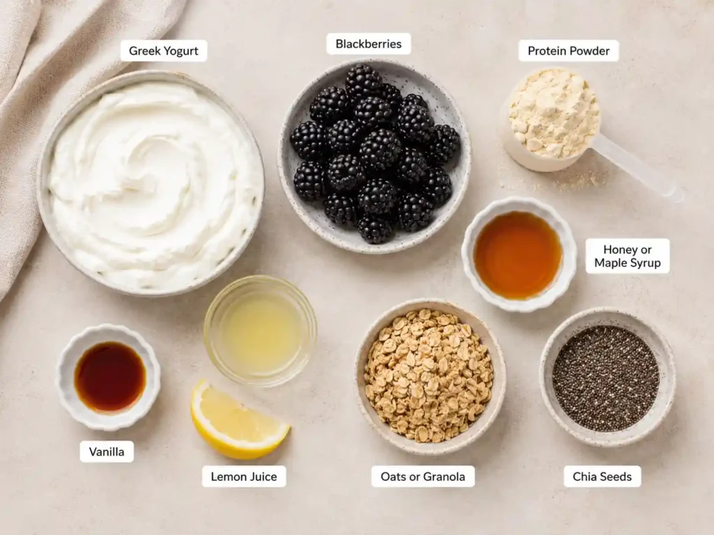 Labeled ingredients for blackberry Greek yogurt protein cups including Greek yogurt, blackberries, protein powder, honey, vanilla, lemon juice, oats, and chia seeds.