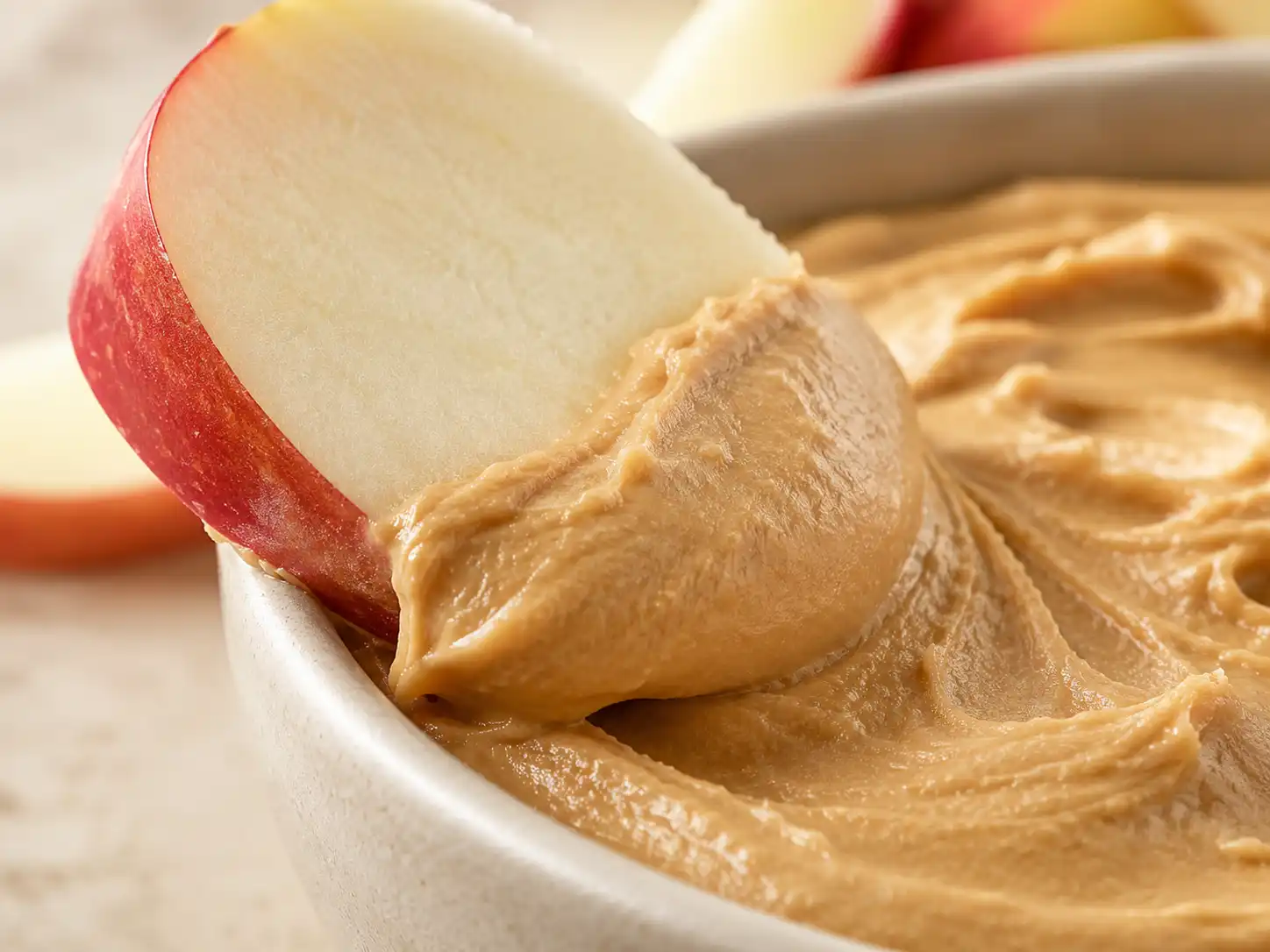 Close-up of thick and creamy Greek yogurt peanut butter dip coating an apple slice