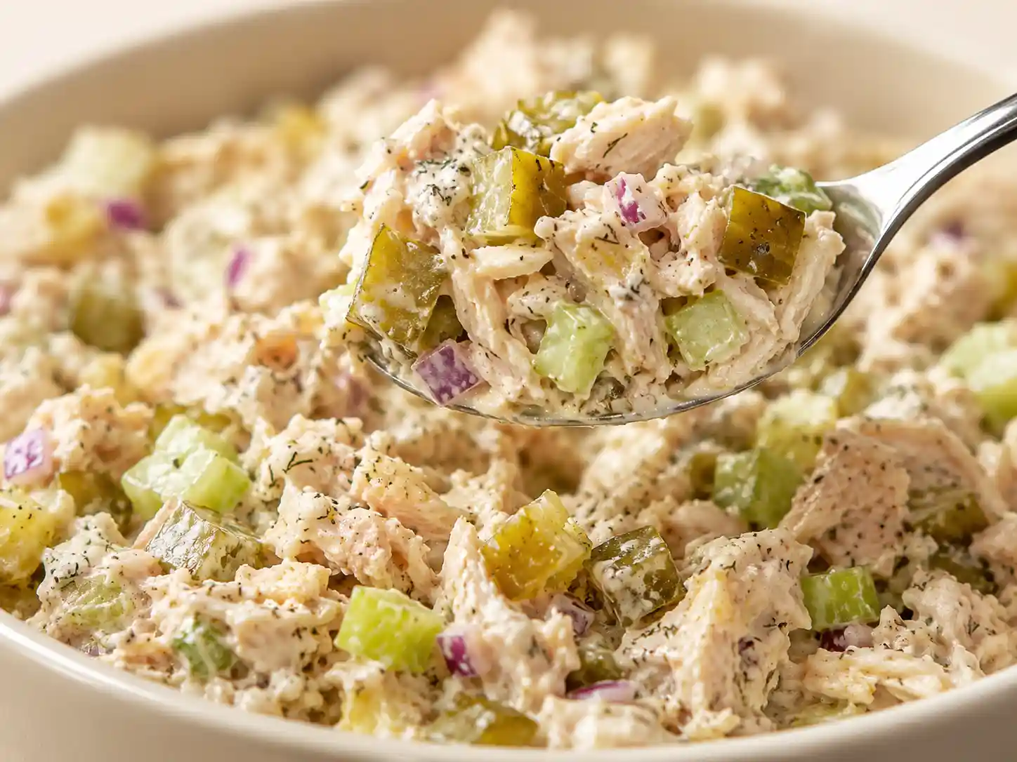 Close up of creamy bread and butter pickle chicken salad with visible pickles and celery