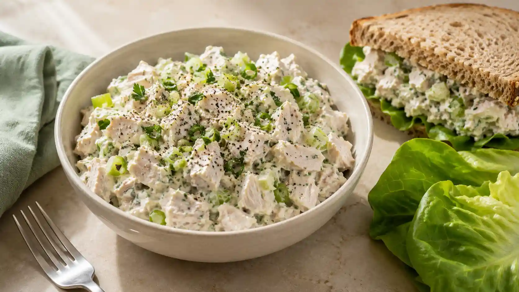 Creamy Greek yogurt chicken salad with cooked chicken, celery, green onion, and fresh parsley in a cream bowl.