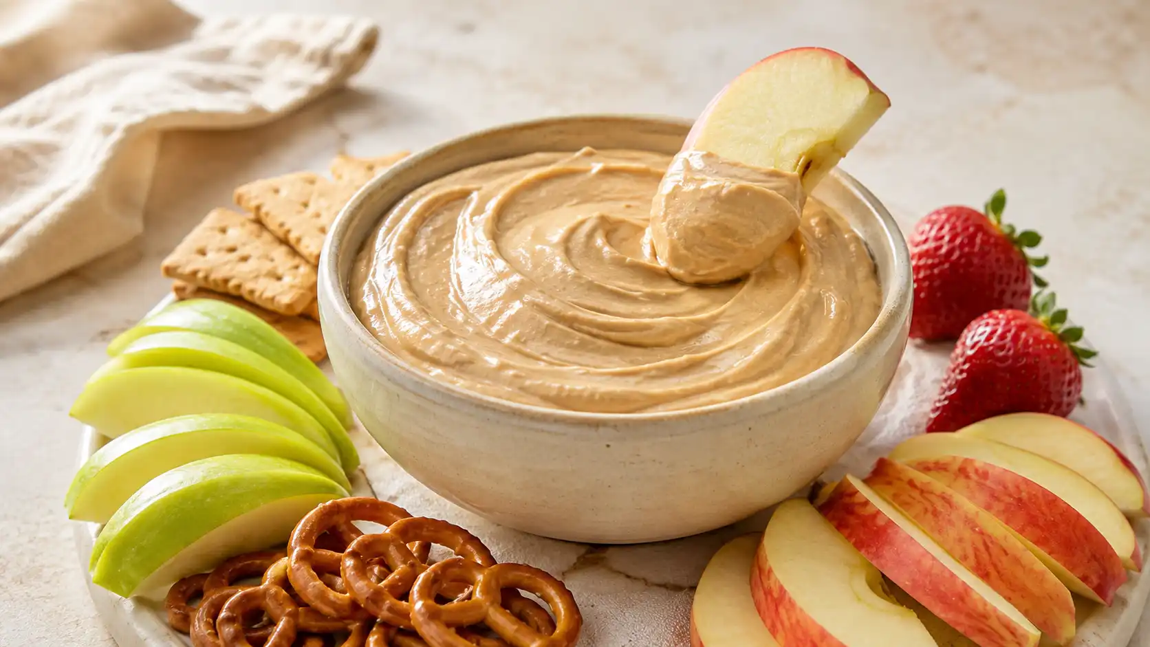 Creamy Greek yogurt peanut butter dip served with apple slices, strawberries, and pretzels