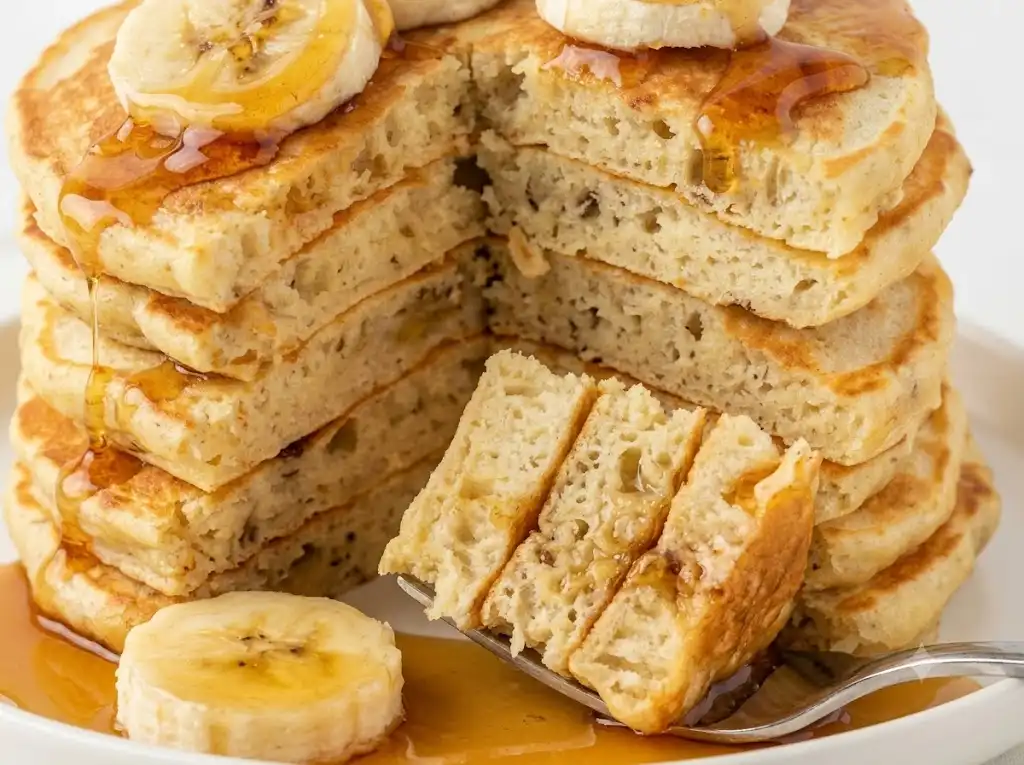 Close-up of a sliced banana oat protein pancake showing its cooked center and oat flecks