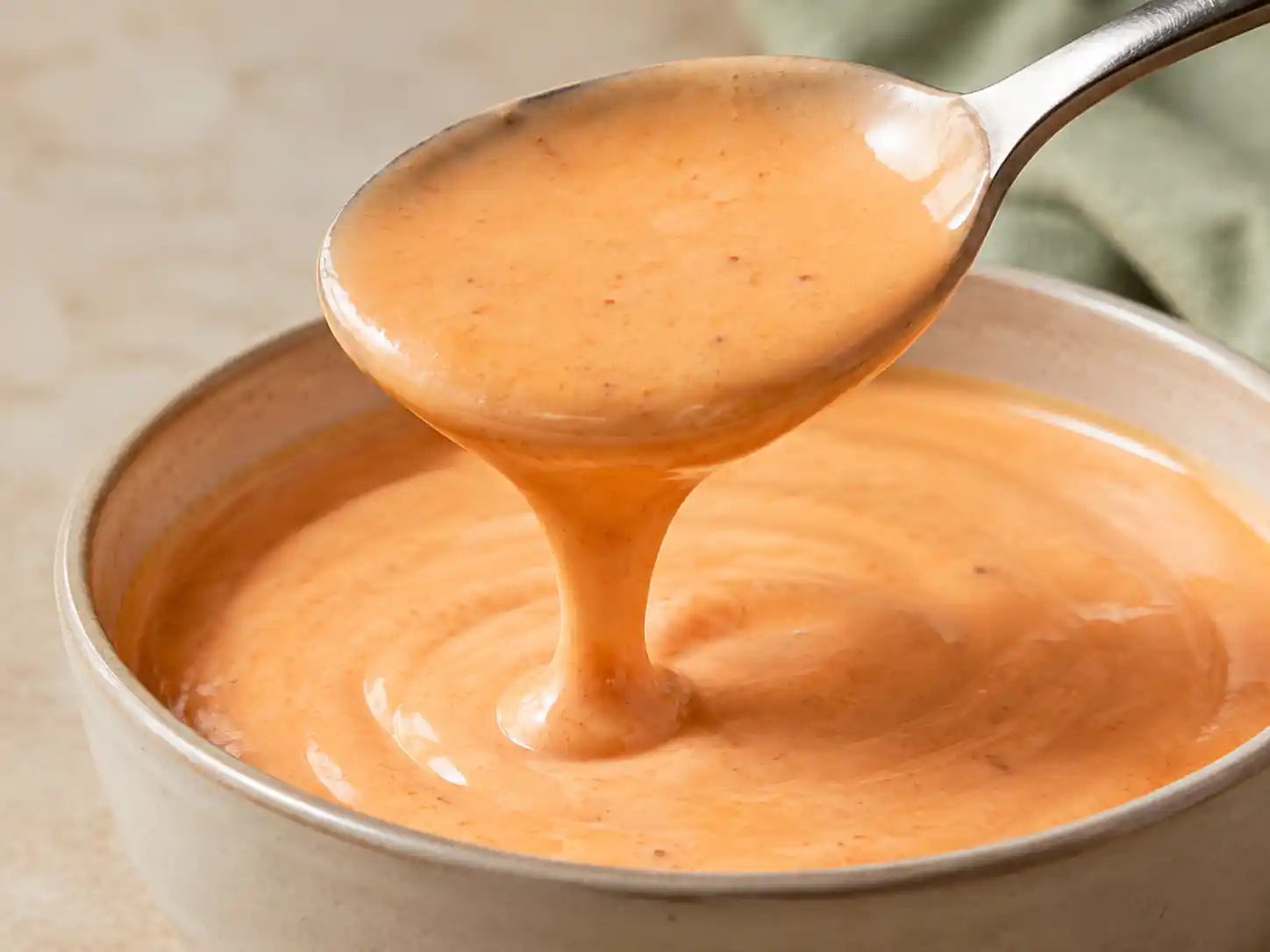 Close-up of thick creamy bang bang sauce falling from a spoon